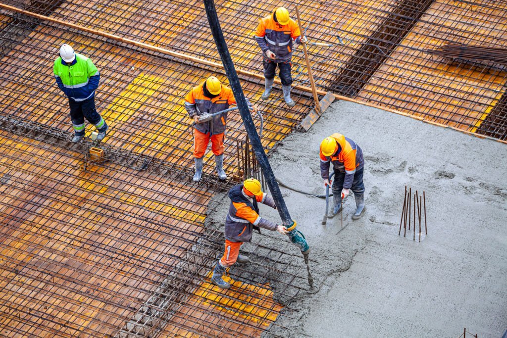 Бригада бетонщиков заливает плиту фундаментную бетононасосом АБН промышленным