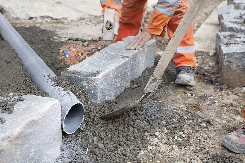 Дорожные работы: засыпка лопатой бордюра и трубы тощим бетоном