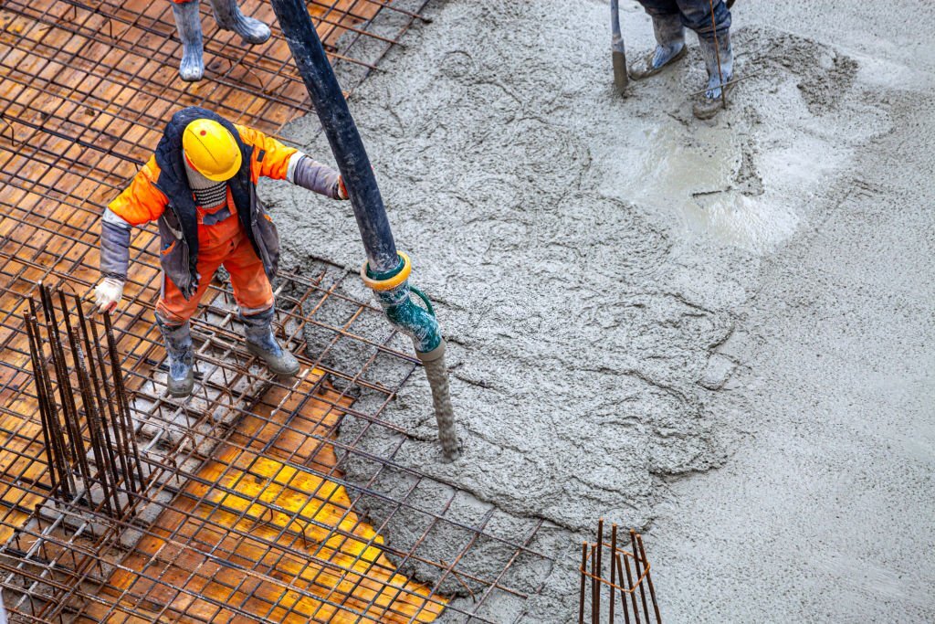 Строитель заливает товарный бетон для АБН бетононасосом в московском районе
